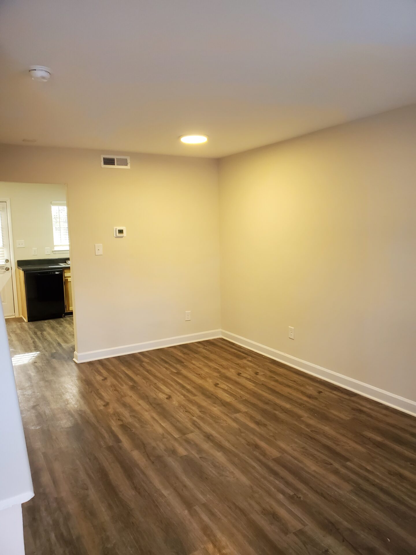 An Empty Room With Wood Flooring and White Walls